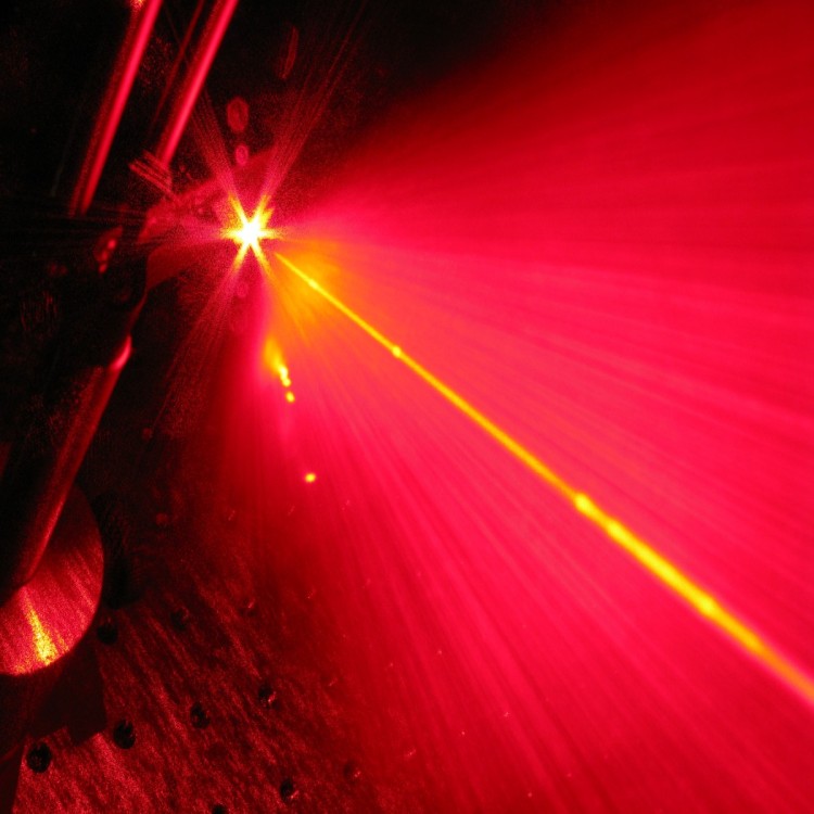 A random laser flash of light. A random laser (red) shines light in all direction while it is pumped by a standard unidirectional laser (yellow).