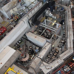 Huge lab to measure tiny proton. Top view of the laboratory, the <i>accelerator hall</i>, at Paul Scherrer Institute. The proton experiment is in the lower left corner, where we see the curved <i>muon extraction channel</i>, which transports the muon beam from the cyclotron trap to the target.
